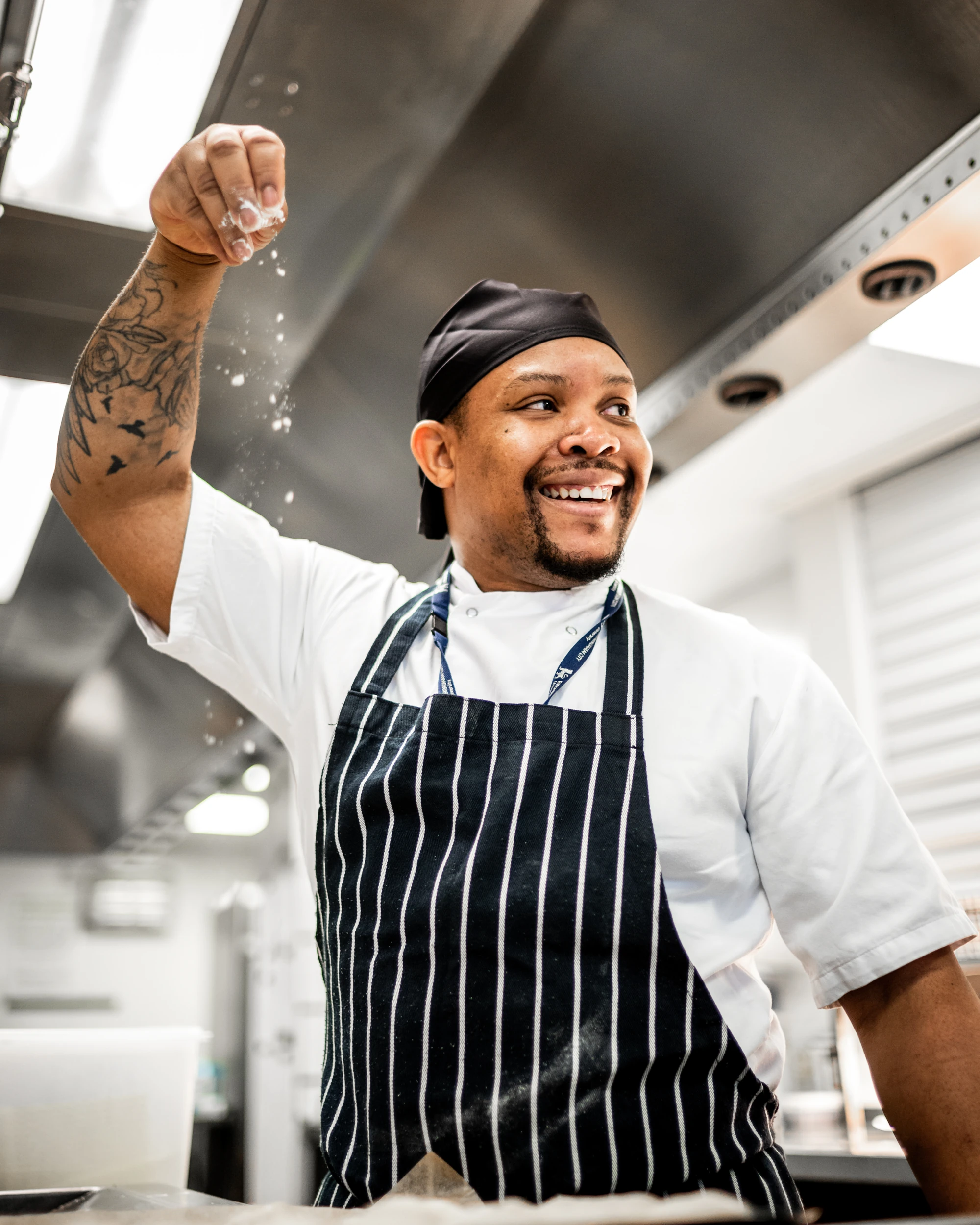 Smiling chef sprinkling ingredients in a kitchen.