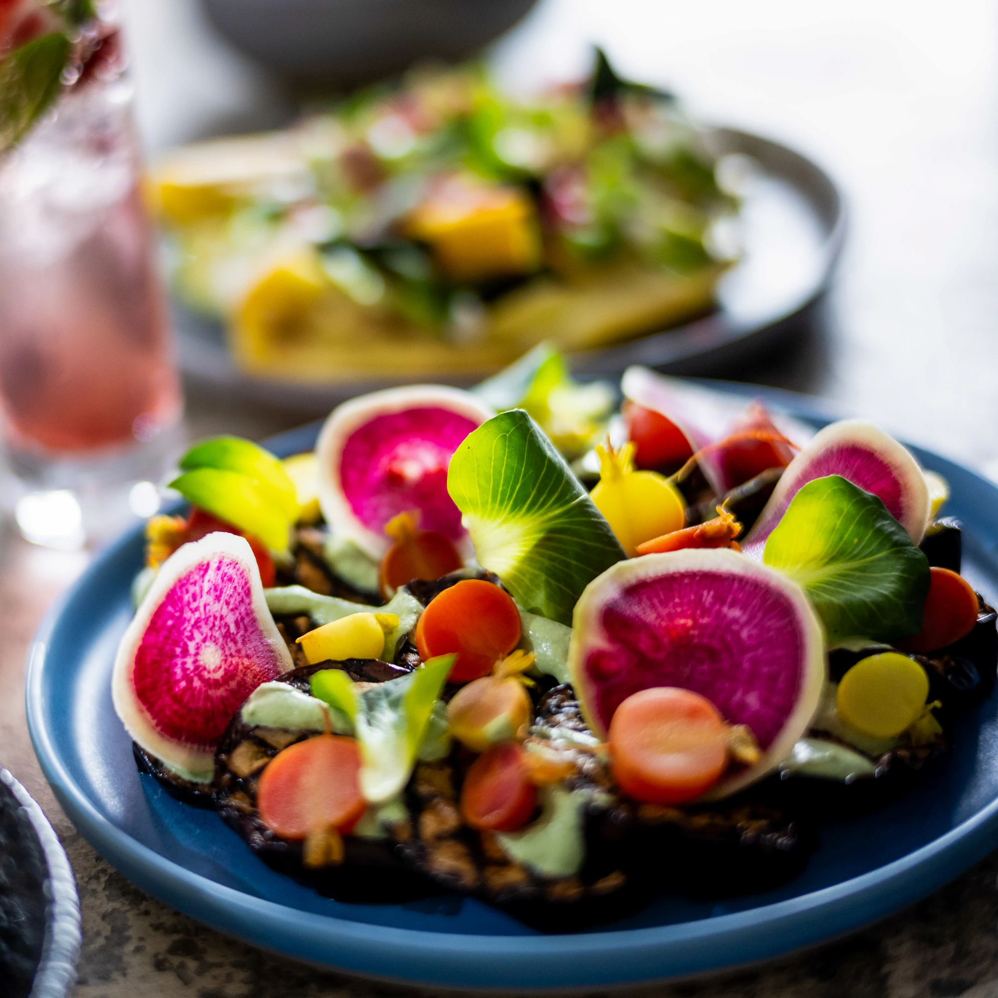 Brightly coloured salad with radishes on a blue plate.