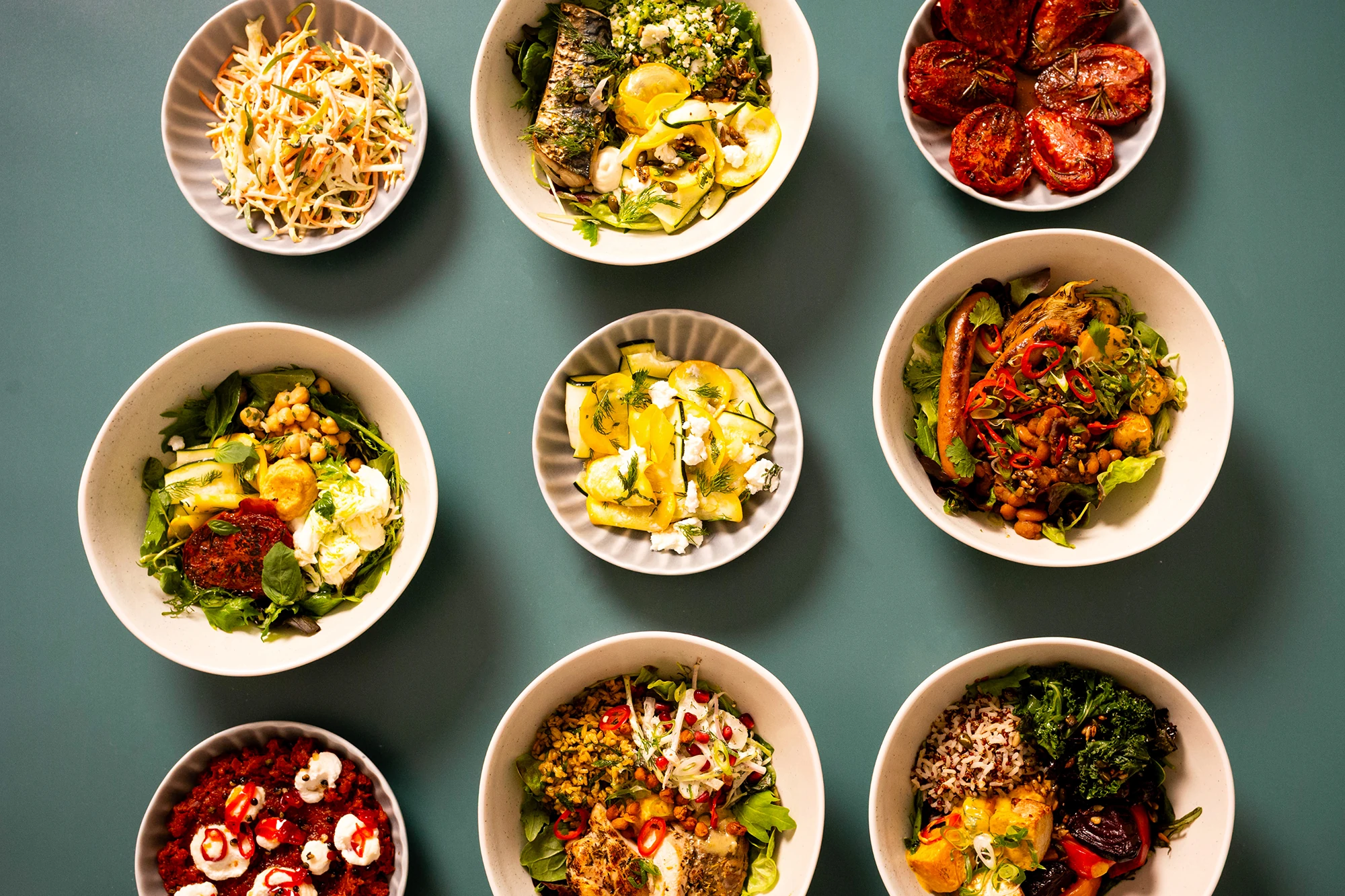 A grid of nine healthy bowls containing various colourful salads and meals.
