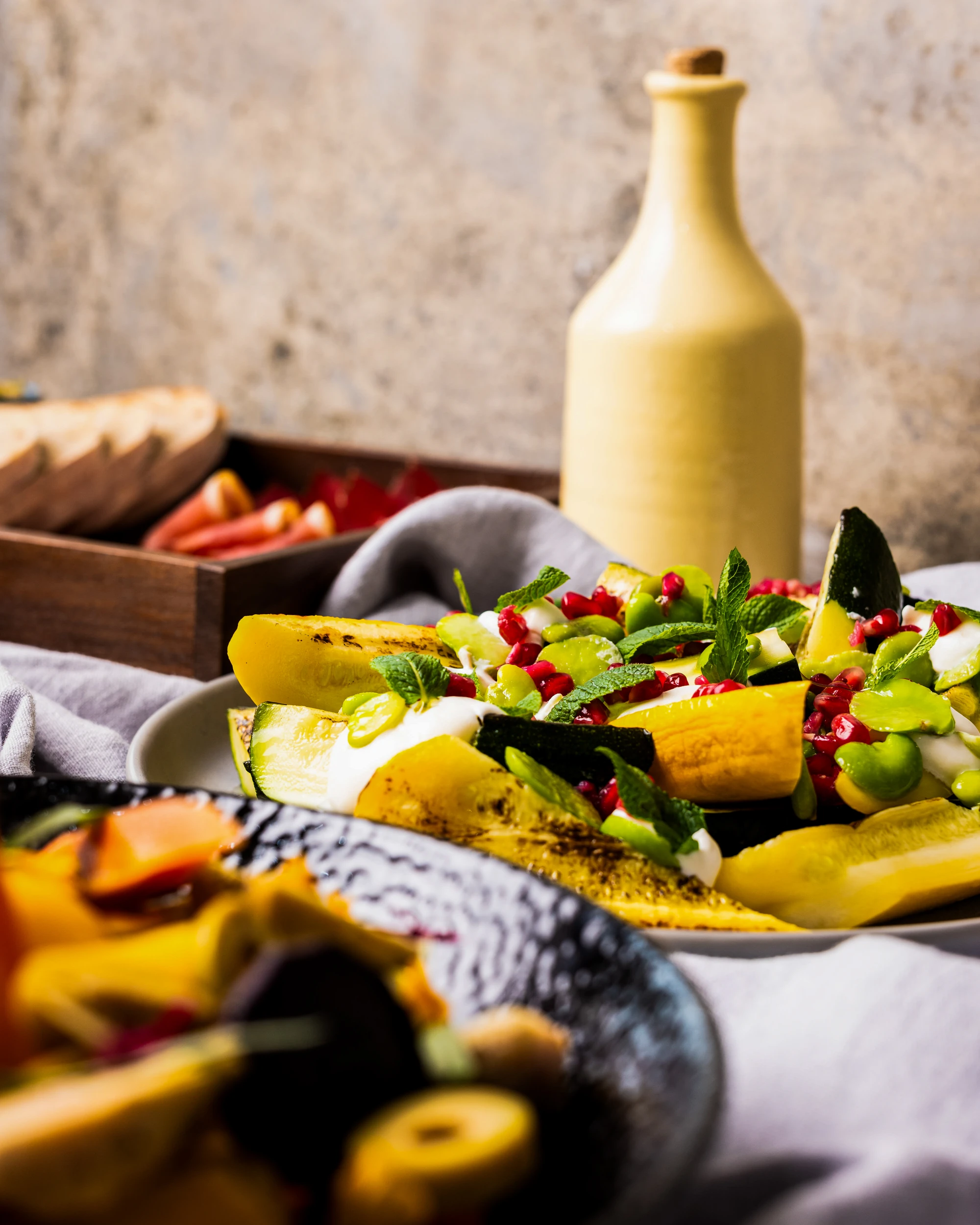 Gourmet plated vegetables and a tall yellow oil bottle.